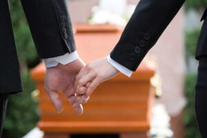 couple at funeral holding hands consoling each other in view of the loss